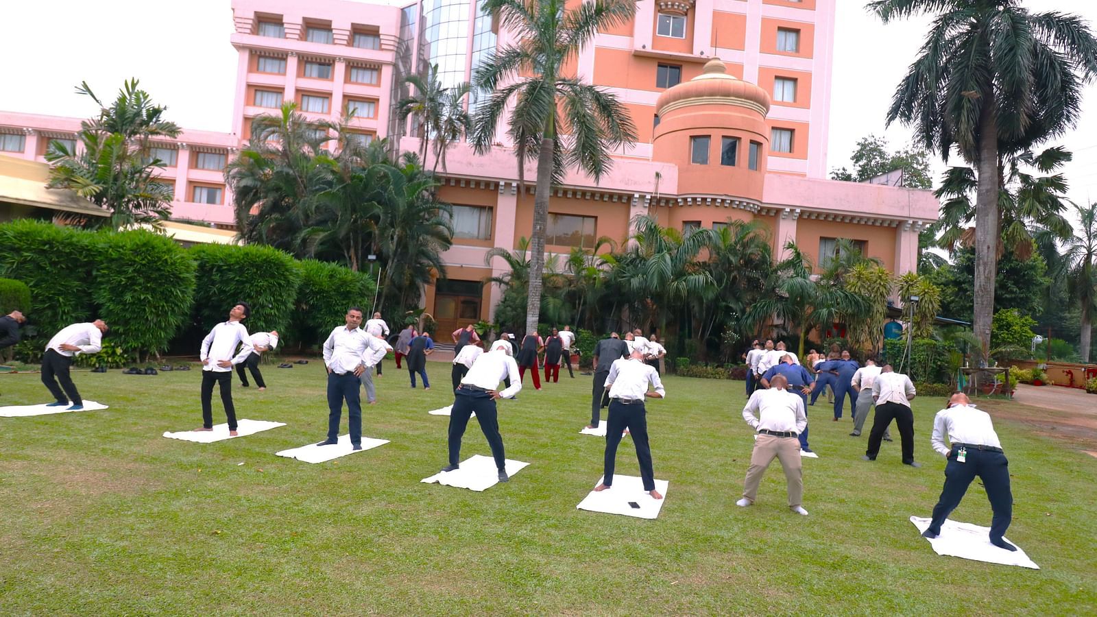 People practising yoga in the garden area at Swosti Resorts on a sunny day