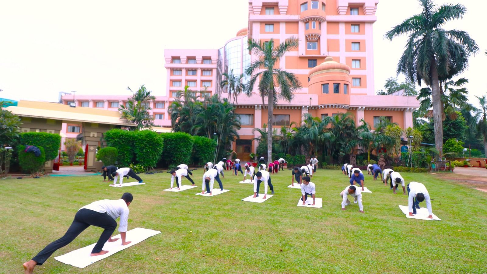 People practising yoga in the garden area at Swosti Resorts on a sunny day