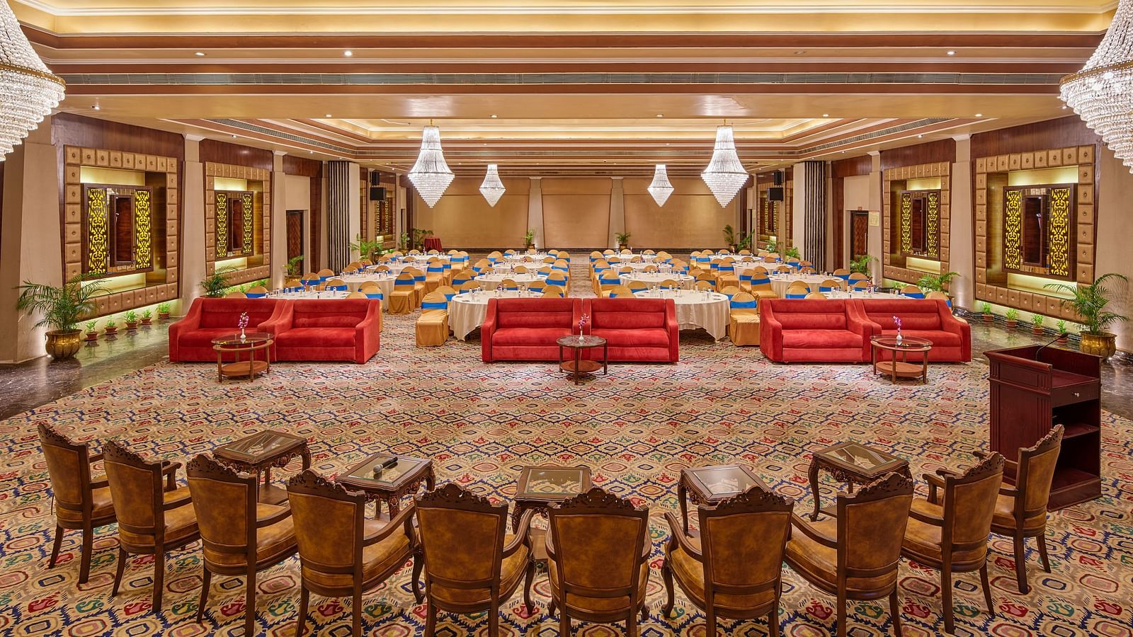 The banquet hall, brightly illuminated and beautifully decorated, is prepared for a memorable celebration.