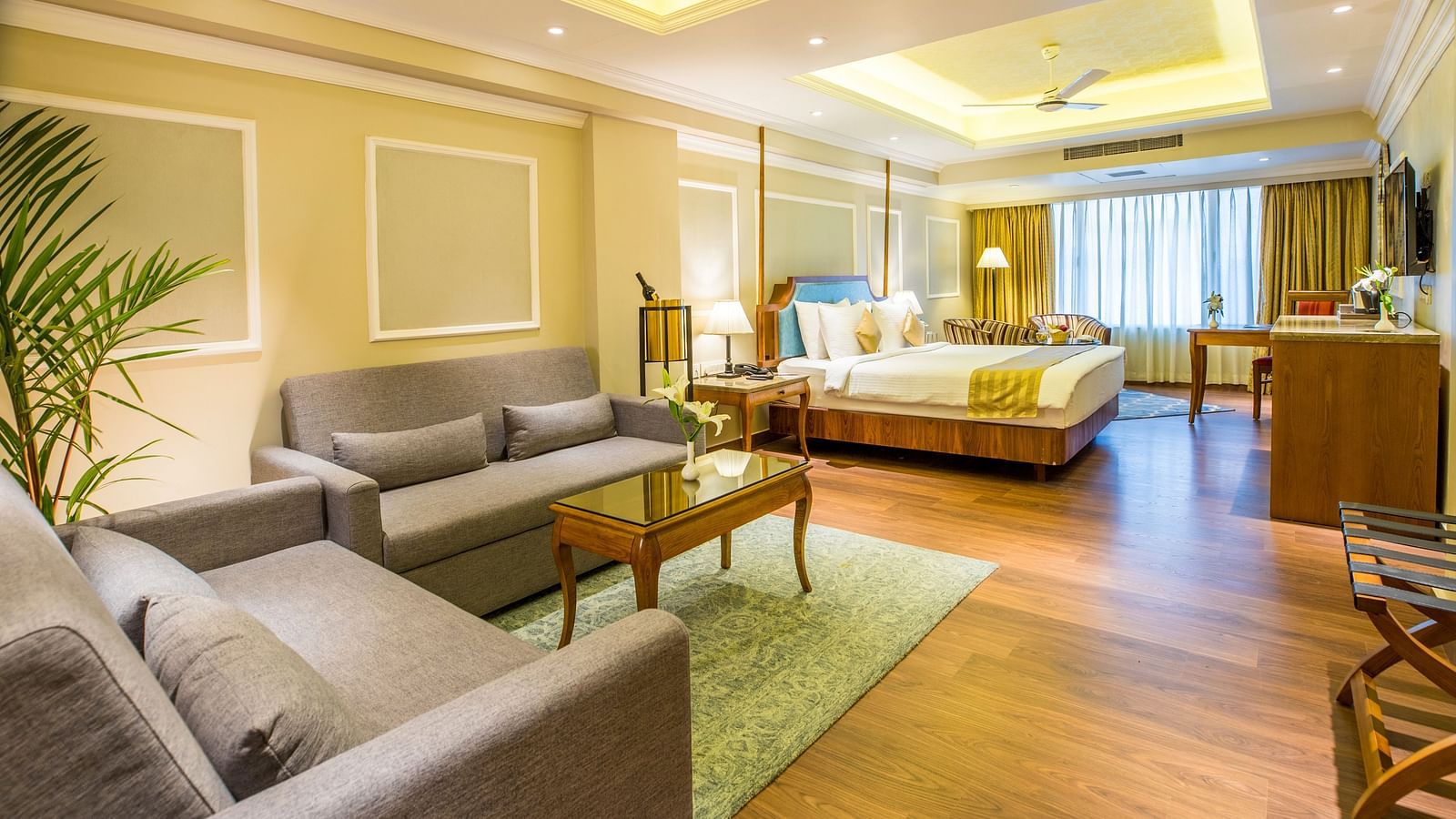 Large sofas and a wooden table are placed on a floor mat, illuminated by warm lighting.