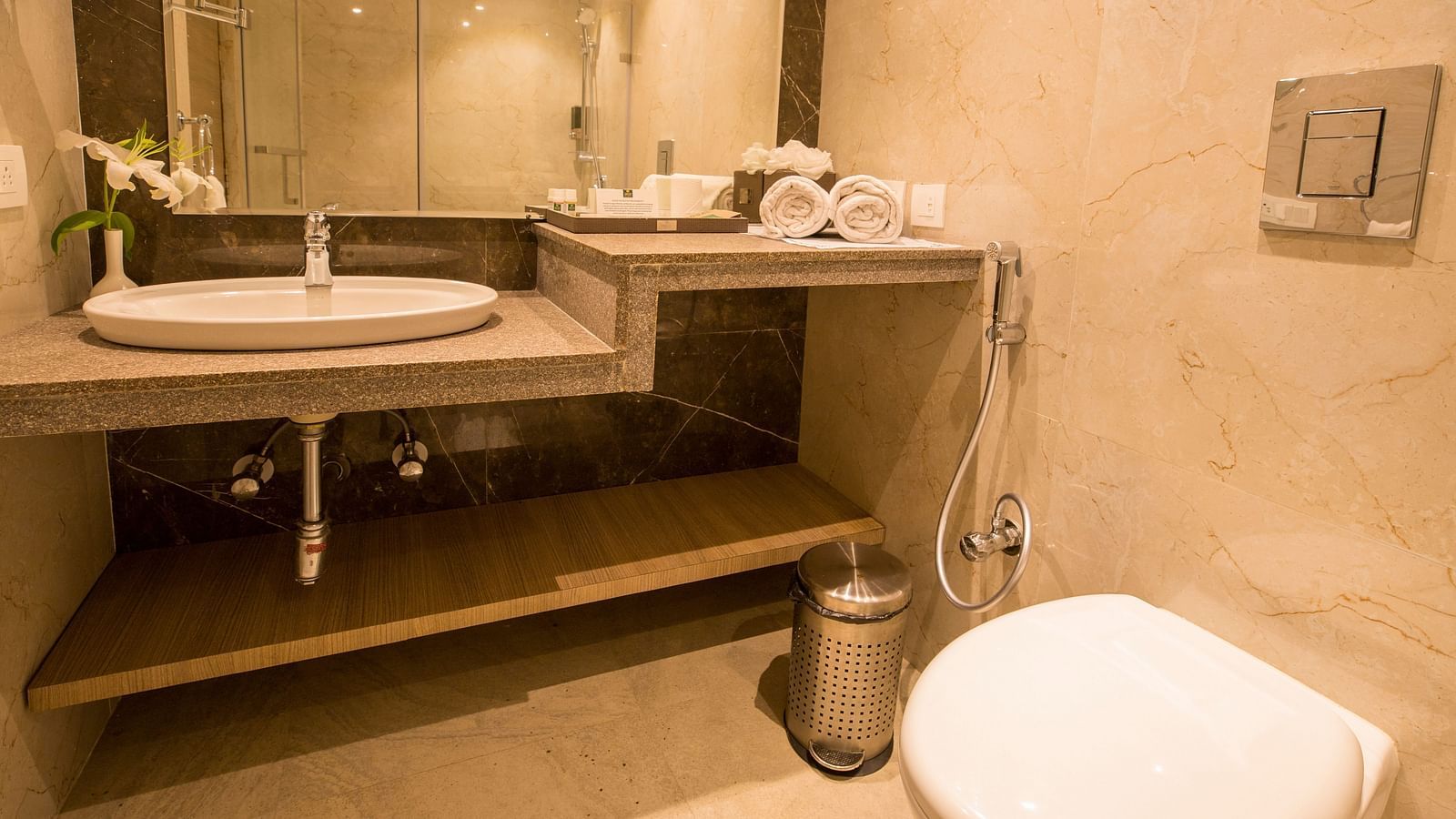 Bathroom with bright lighting and a large mirror set horizontally above the washbasin.
