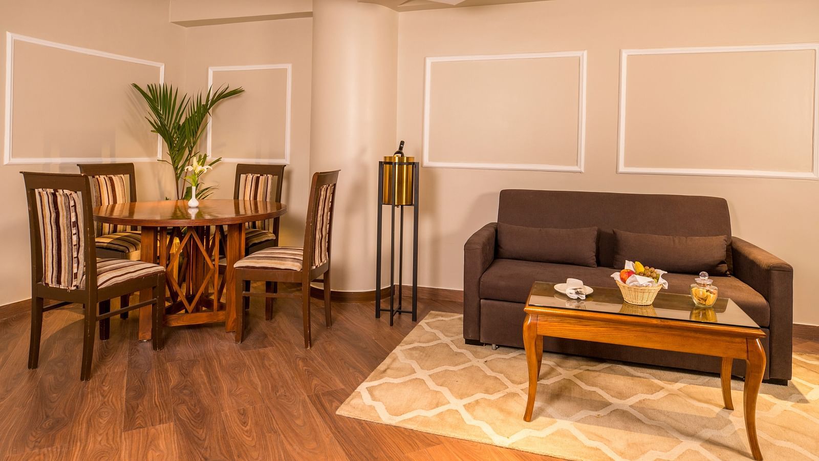  U-shaped cushion sofa with a table featuring tea pots and cups on a tray, with a dining table and chairs to the left side.