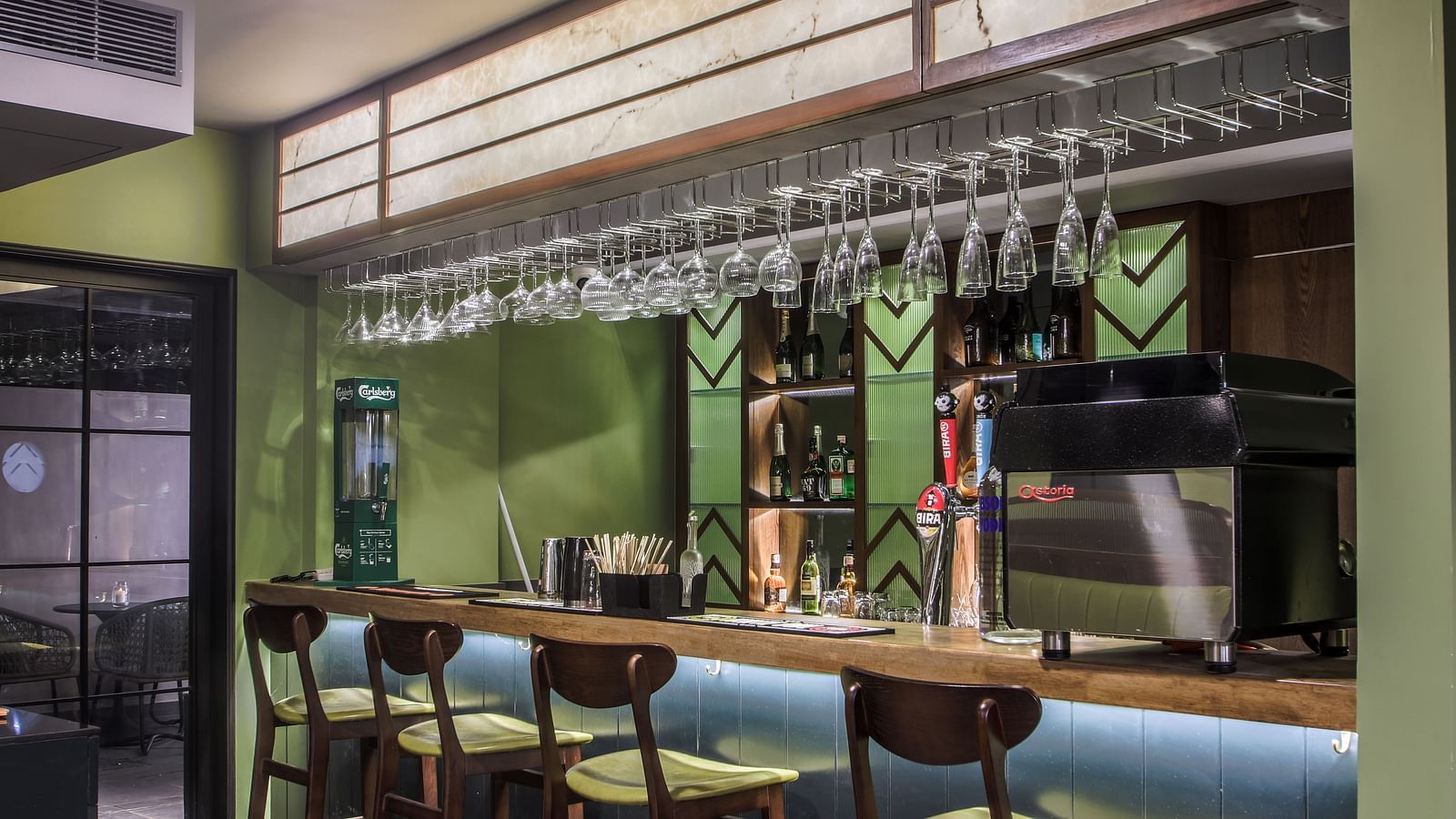 Shot of a bar with a wooden countertop, green walls, and a row of stools  | T24 Retro