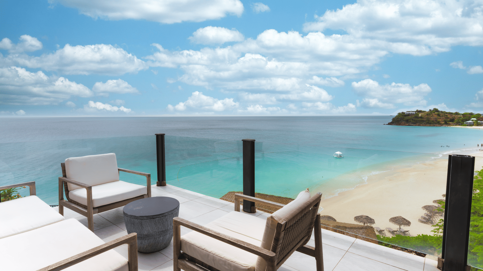 Sea-facing outdoor seating area with 2 cushioned chairs and a table overlooking the coastline at Ocean 19, Tamarind Hills Resort and Villas.