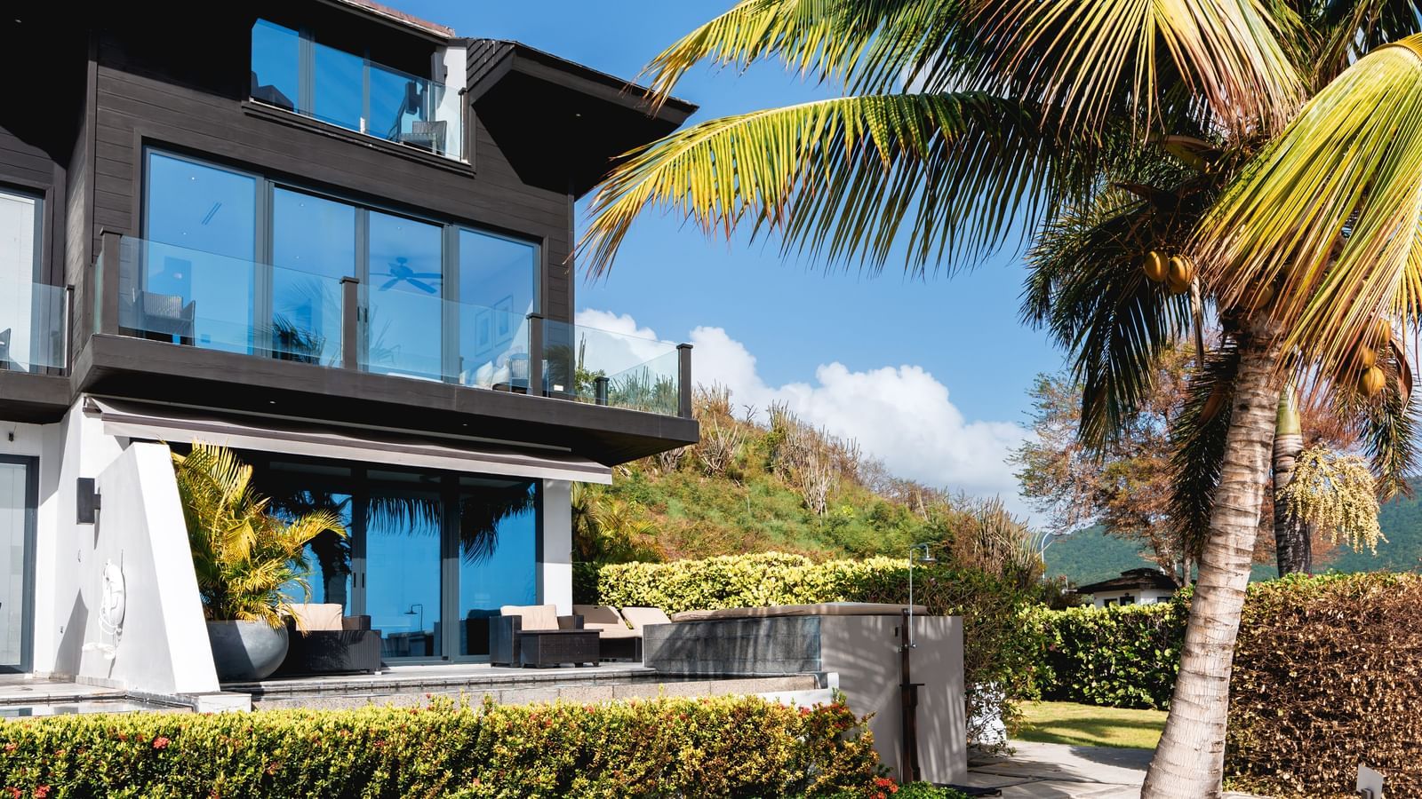 An exterior shot of the villa with clear sky in background and trees all around.