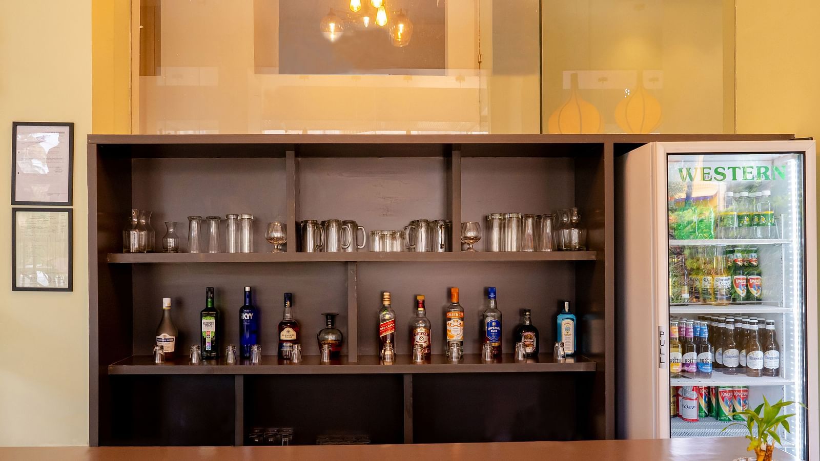 A well-organized bar with various bottles of alcohol displayed on shelves - TGI Ameya Grand, Goa