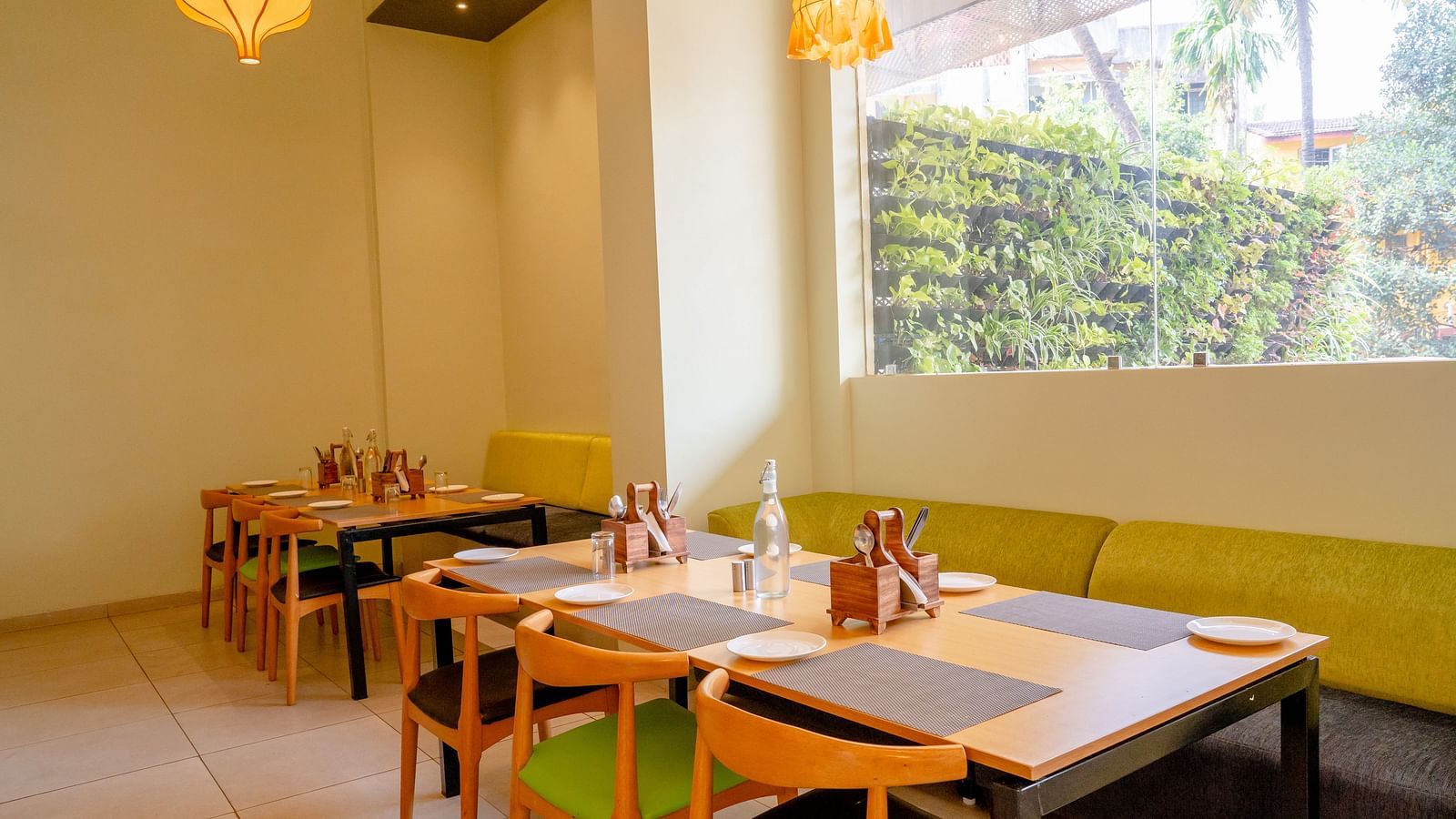 A neatly arranged restaurant dining area with tables, chairs and pendant lights- TGI Ameya Grand, Goa