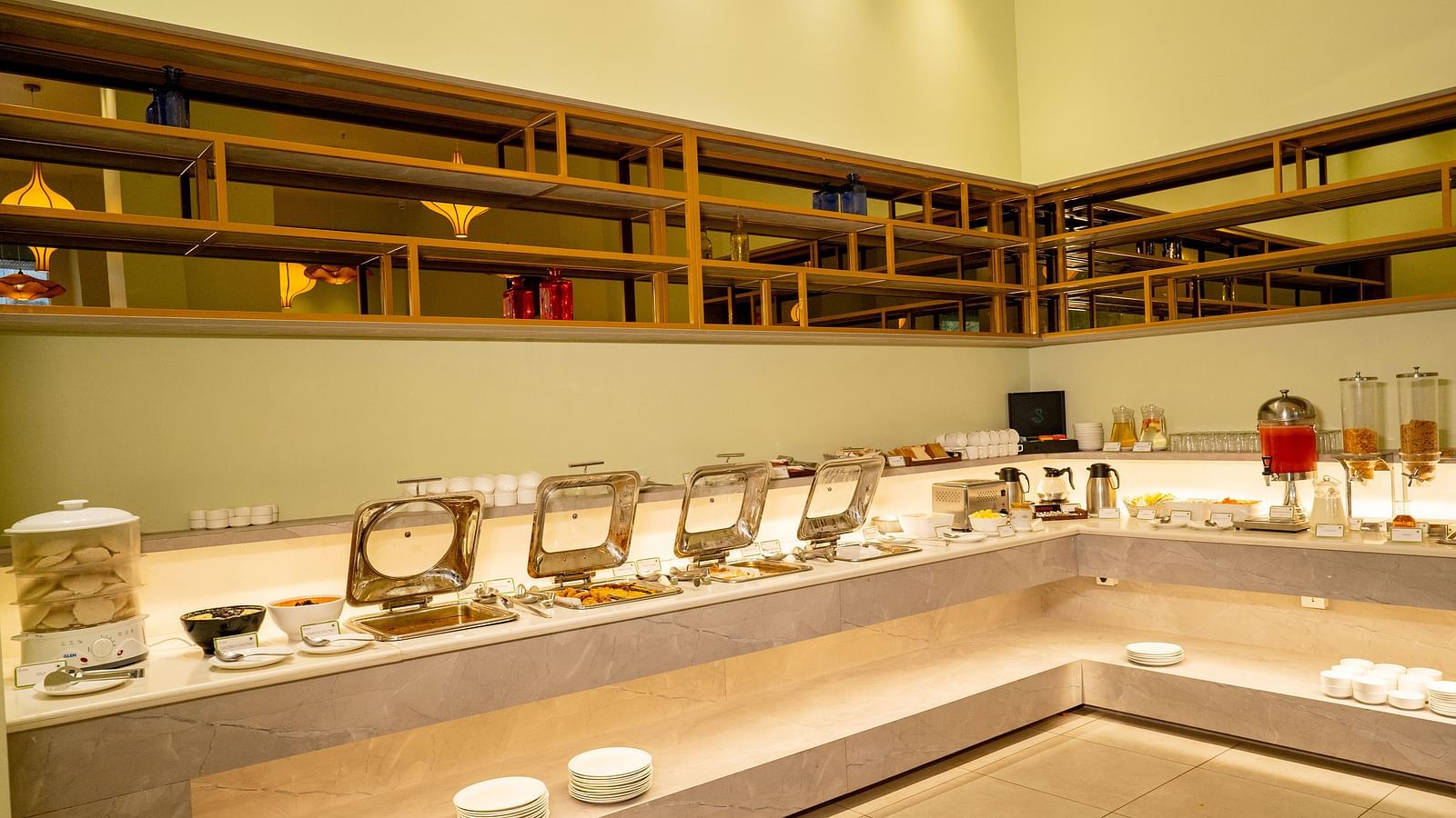 A buffet serving area in a restaurant with chafing dishes and serving utensils - TGI Ameya Grand, Goa