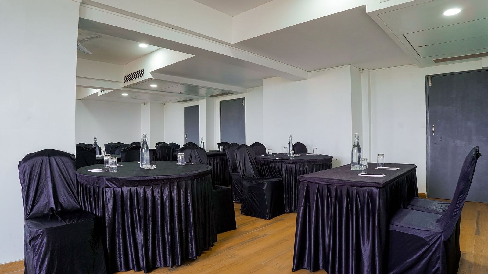 Spacious conference room with round tables and chairs covered in black - TGI Ameya Grand, Goa