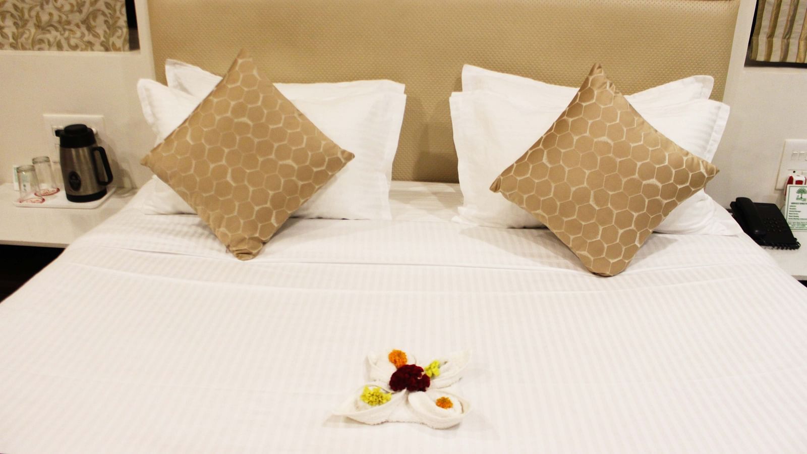 A image of the bed with plush pillows and a elegant design made out of towel and flowers placed on the breadspread - TGI Apple Inn, Jaipur 