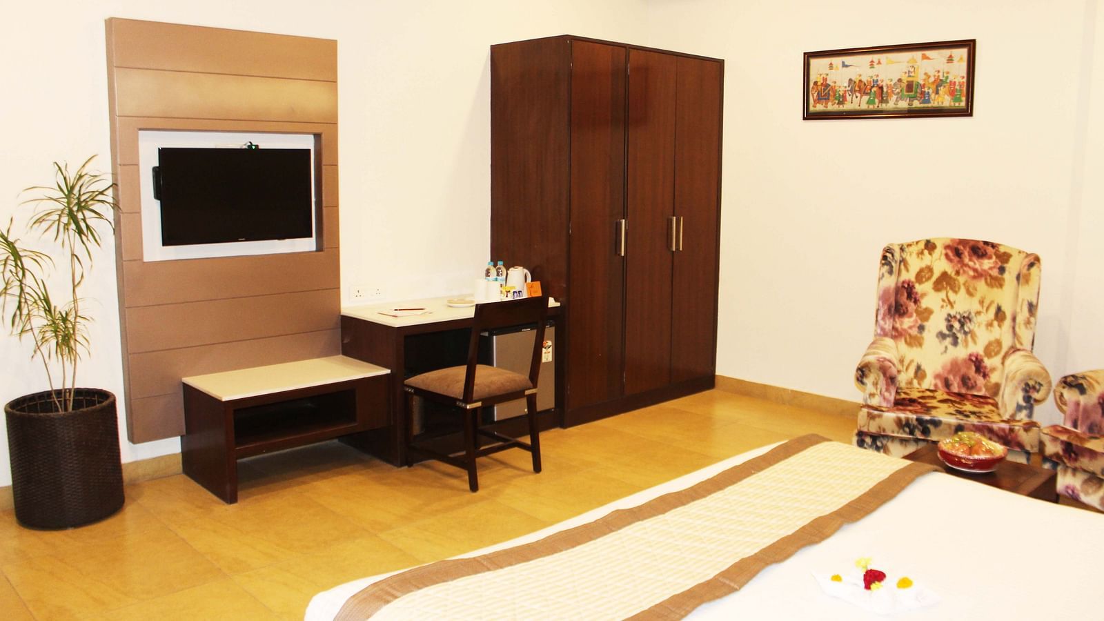 A view of the suite with a comfortable bed, a relaxing chair, a flat TV and furniture - TGI Apple Inn, Jaipur 