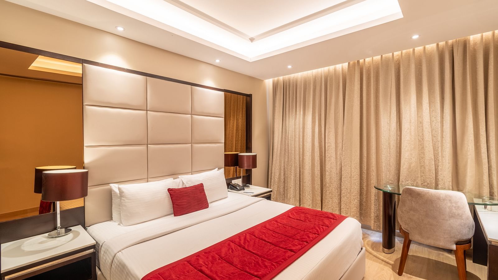 Fortuna suite's bedroom with full-length curtains, bedside table, and armchair- TGI Grand Fortuna, Krishnagiri Main Road, Hosur