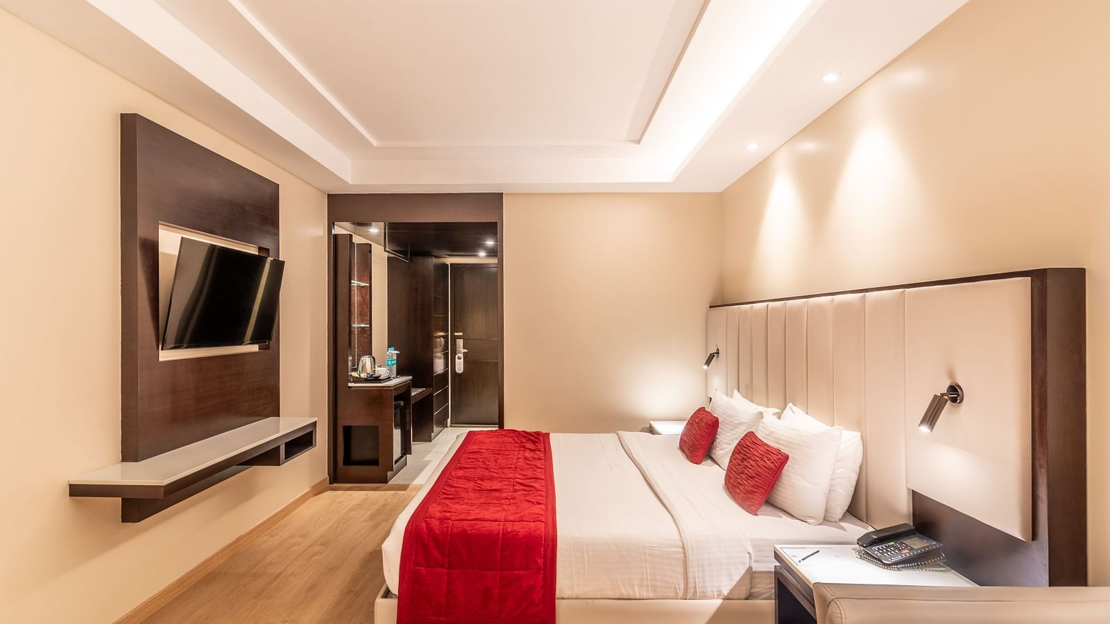 Bedroom with mounted TV, bedside lighting, and seating area- TGI Grand Fortuna, Krishnagiri Main Road, Hosur