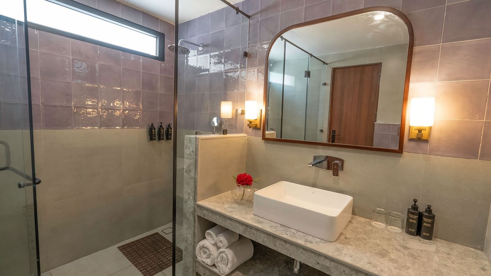 Modern bathroom with a walk-in shower and a sink area separated by a glass door at The Chamomile Estate.