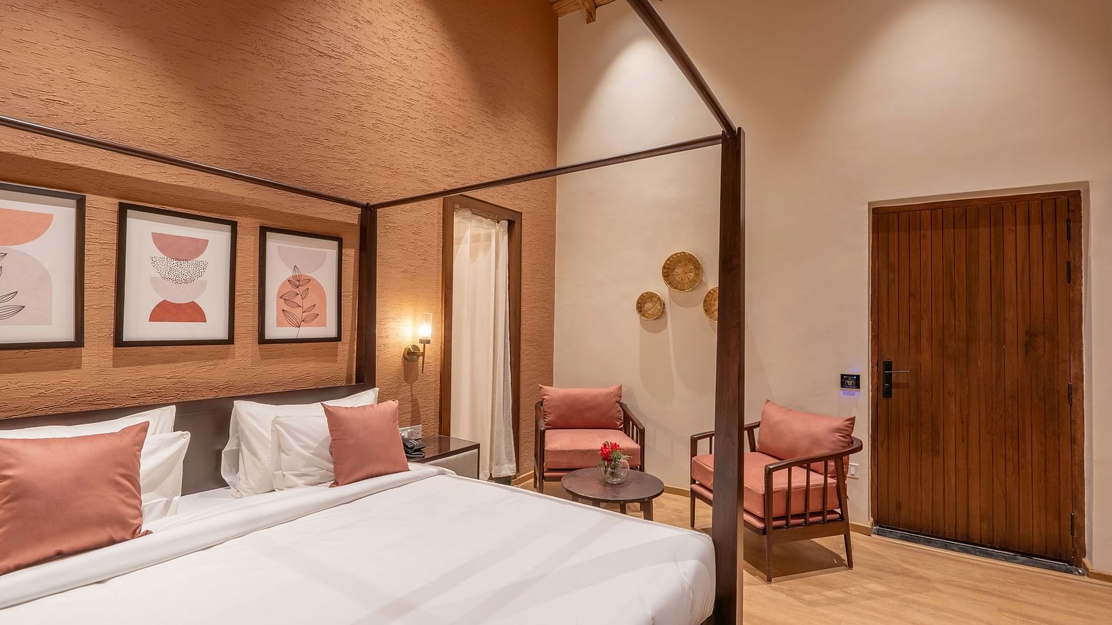 Bedroom with a four-poster bed, photographs above the headboard, and a seating area beside the door at The Chamomile Estate.