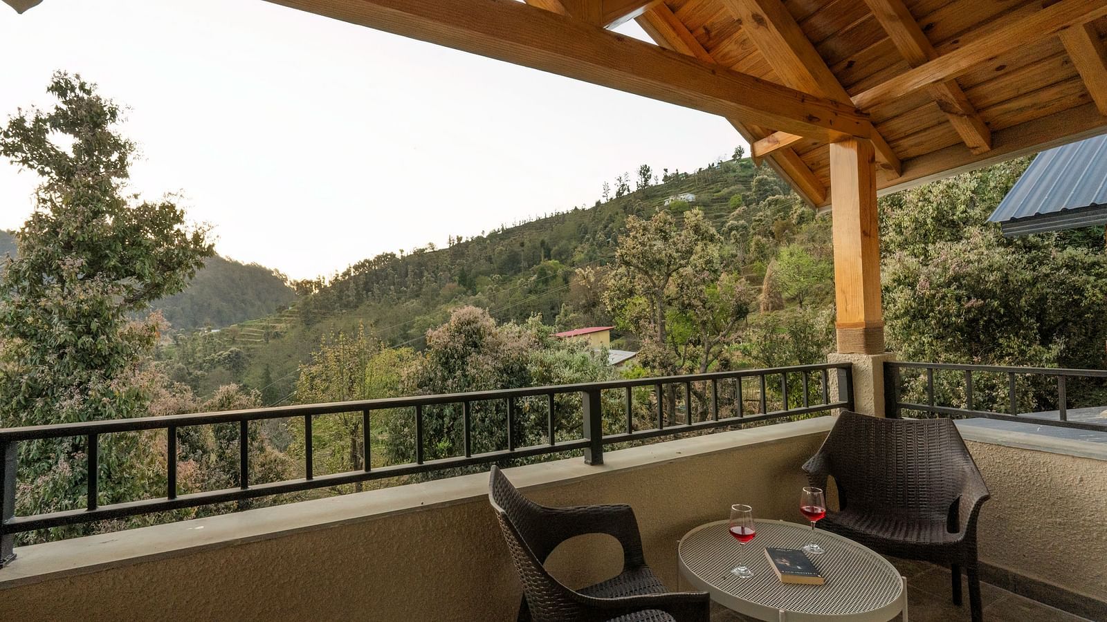 Balcony with outdoor seating and a small round table in the middle, overlooking a scenic mountain view at The Chamomile Estate.