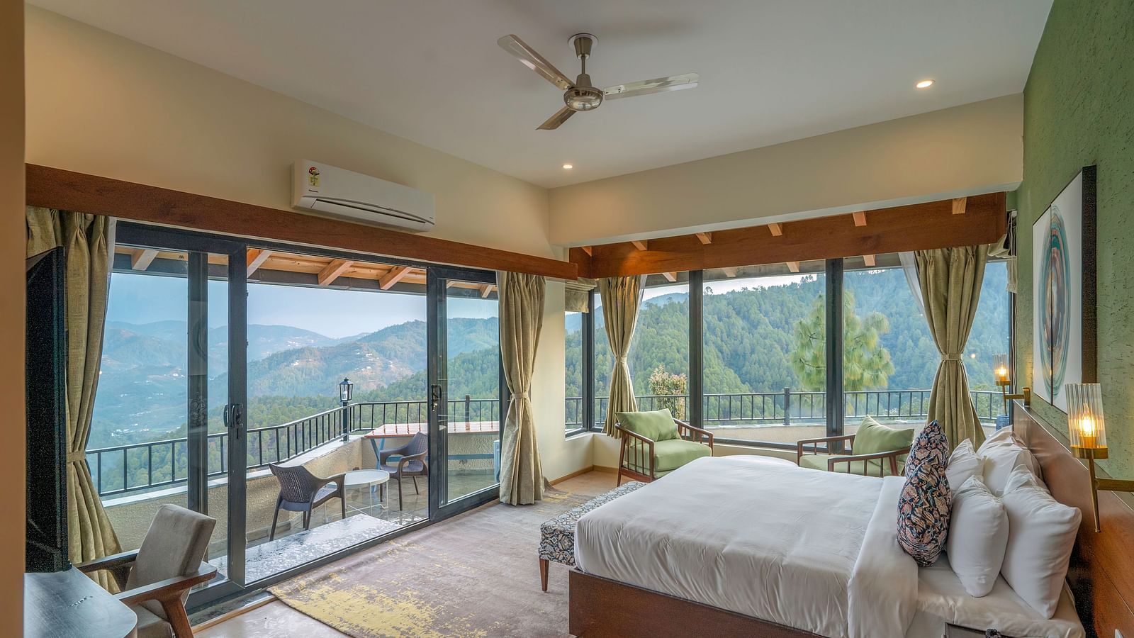 Spacious room with a large bed and a large glass sliding door leading to a balcony with a mountain view at The Chamomile Estate.