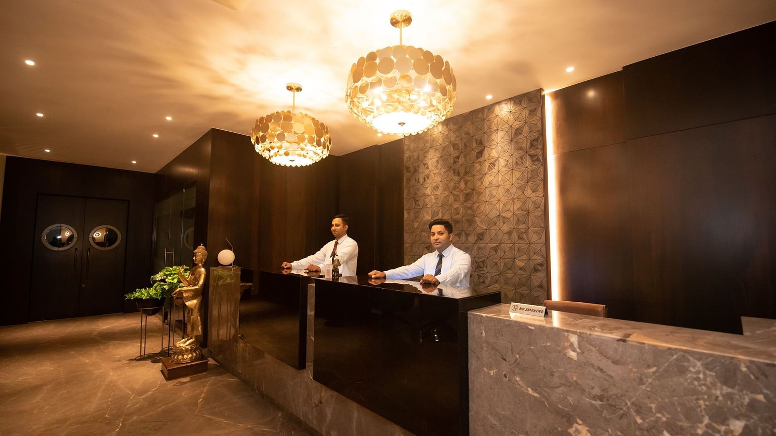 Reception area with two staff members behind the desk - The Cindrella Hotel, Siliguri