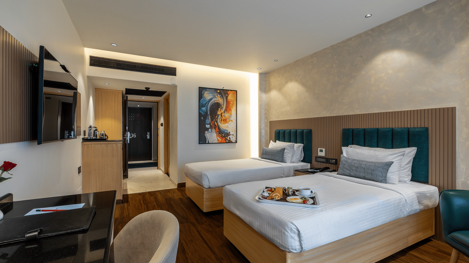 A well-lit hotel room at the Citrine Hotel with twin beds, a TV, and a mirror.