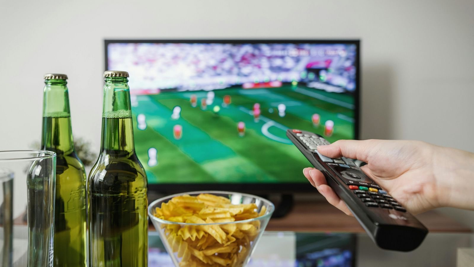 A TV screen displaying a football match, with bottles and snacks nearby.