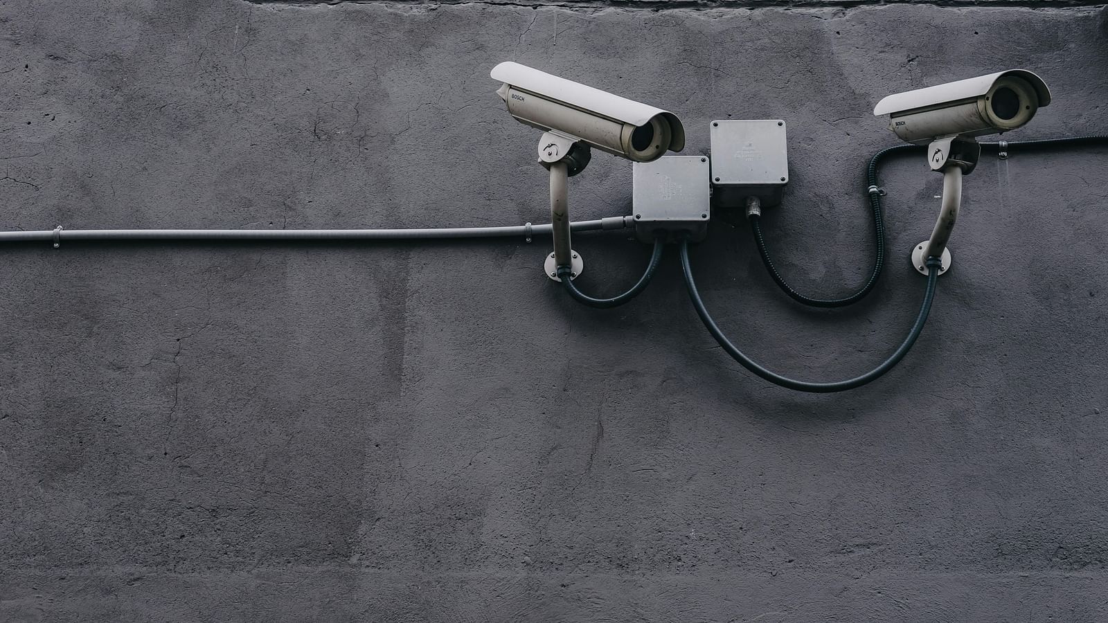 Two security cameras mounted on a grey wall.
