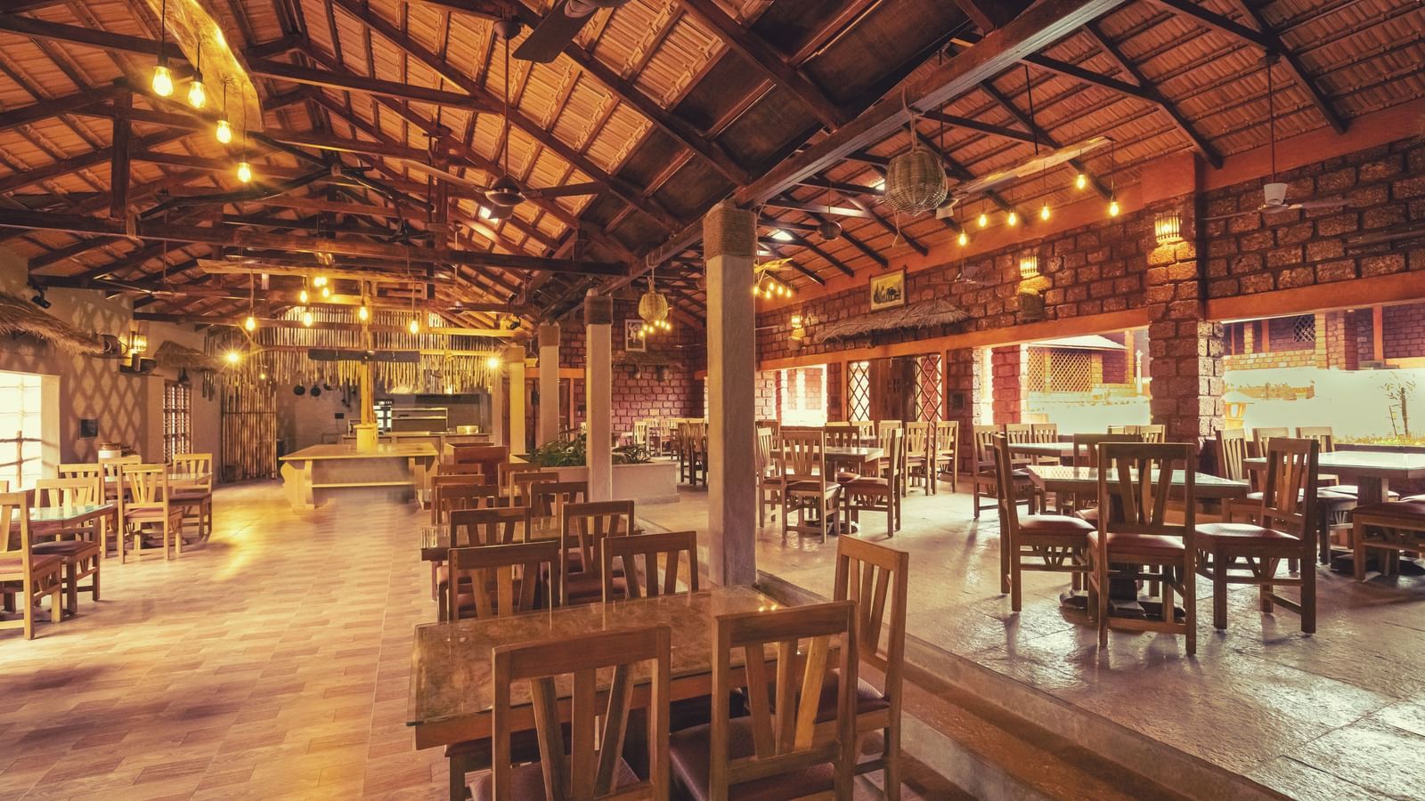 An interior shot of a spacious dining area with high wooden ceilings and multiple tables and chairs at The Copper Edge - Eco Resort, Coorg.