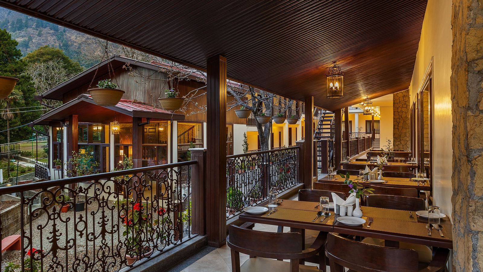 tables set up beside a wall on a balcony and flower pots hanging from the ceiling by the railing - The Earl's Court, Nainital