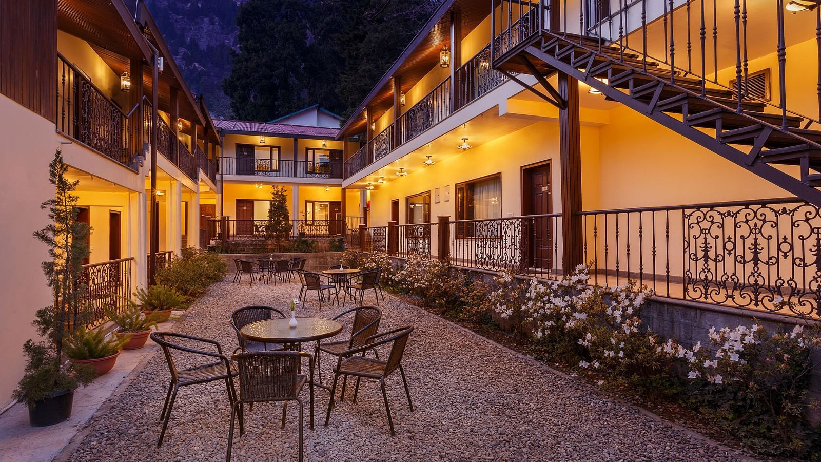 interior of the property with tables and chairs in clusters with flowers and plants on each side of the path - The Earl's Court, Nainital