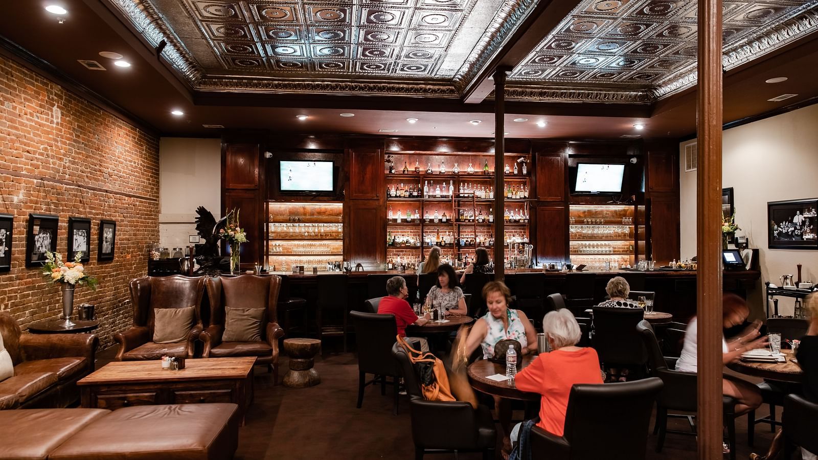 A spacious restaurant interior with tables, booths, high ceilings, and a large bookshelf along one wall.- The Grand Hotel & Ballroom, McKinney