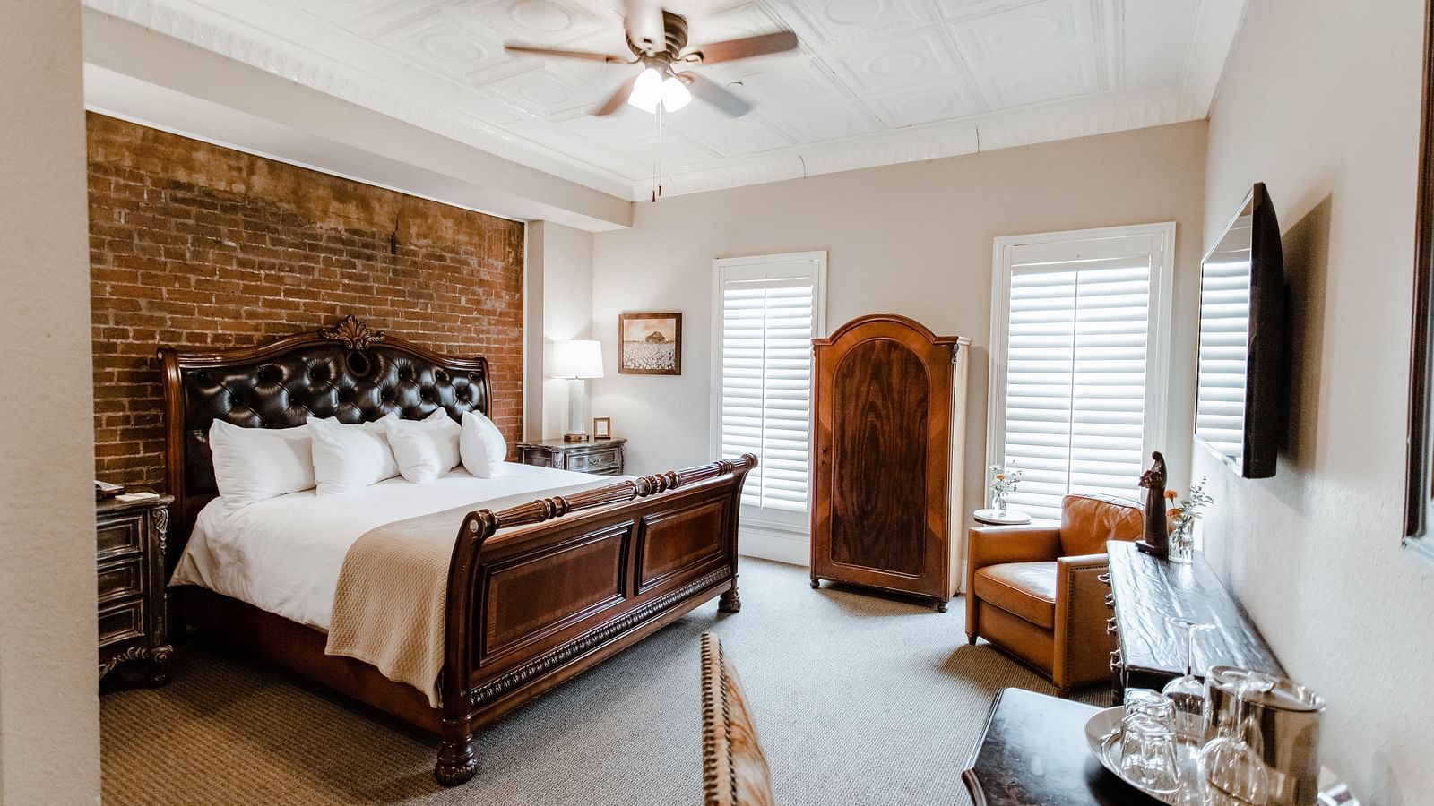 A spacious bedroom with a leather chair, modern decor, and a large bed, creating a stylish and comfortable living space - The Grand Hotel & Ballroom, McKinney