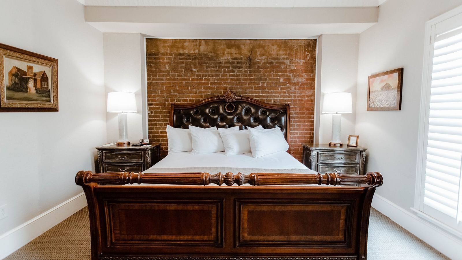  A classic bedroom with dark wood furniture, a large bed, and soft, natural lighting from the window, providing a serene retreat - The Grand Hotel & Ballroom, McKinney