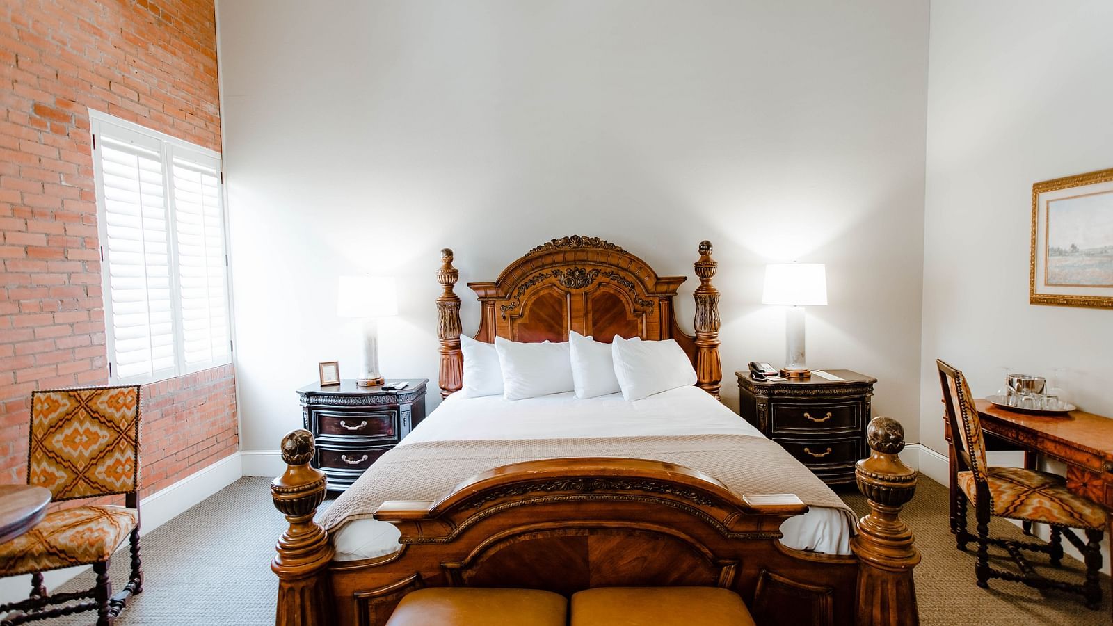A stylish bedroom featuring a large wooden bed, soft lighting, and elegant decor, creating a relaxing and warm atmosphere - The Grand Hotel & Ballroom, McKinney