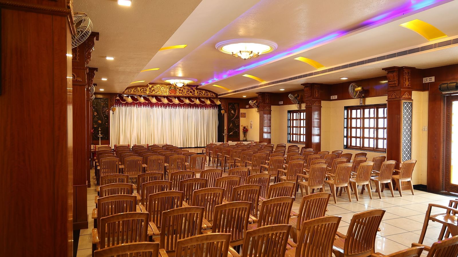 corner view image of the banquet hall with a lot of brown coloured chairs arranged at The Grand Krishna Rooms