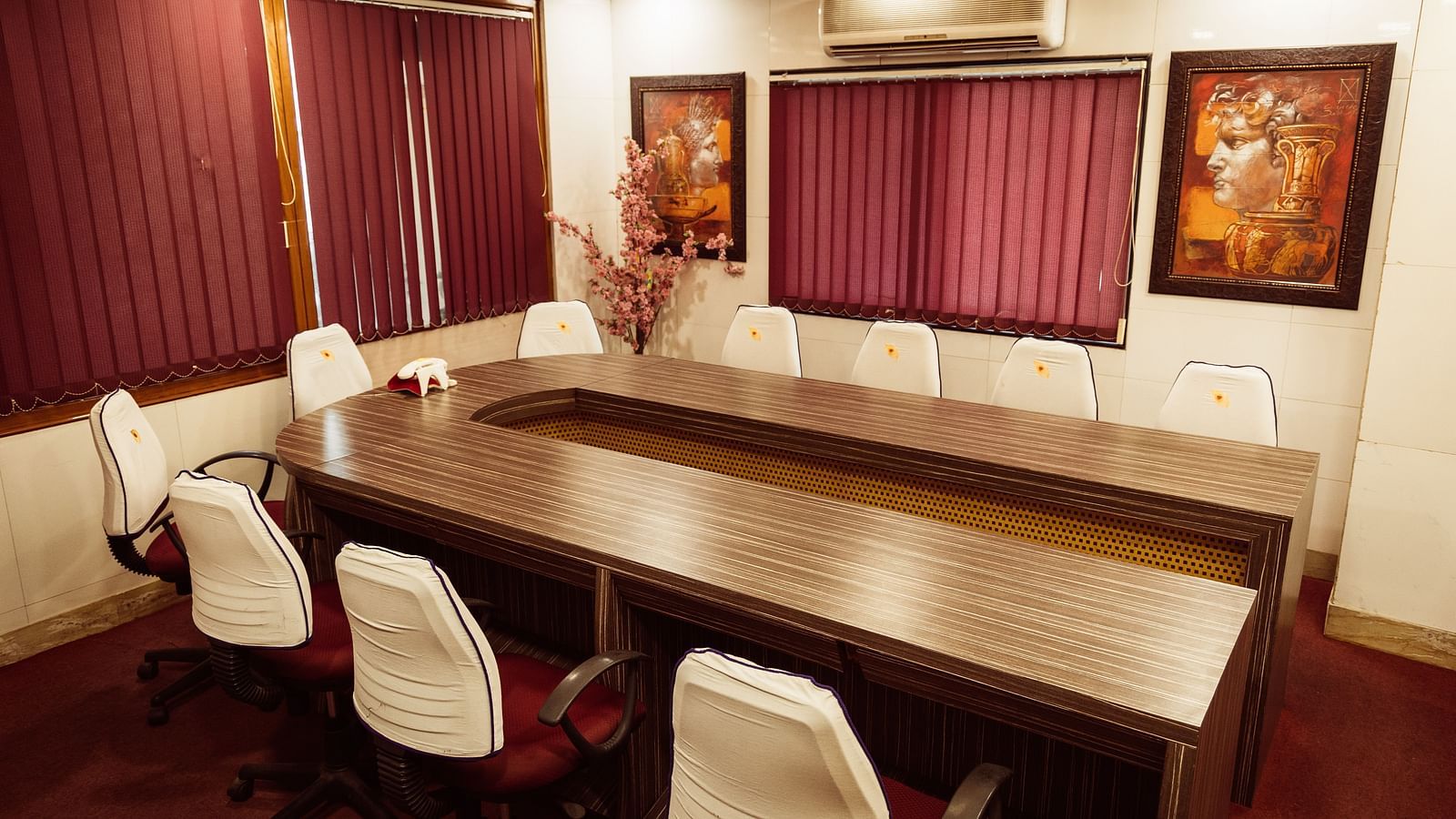image of the boardroom featuring a conference table with white chairs arranged around it at The Grand Krishna Rooms