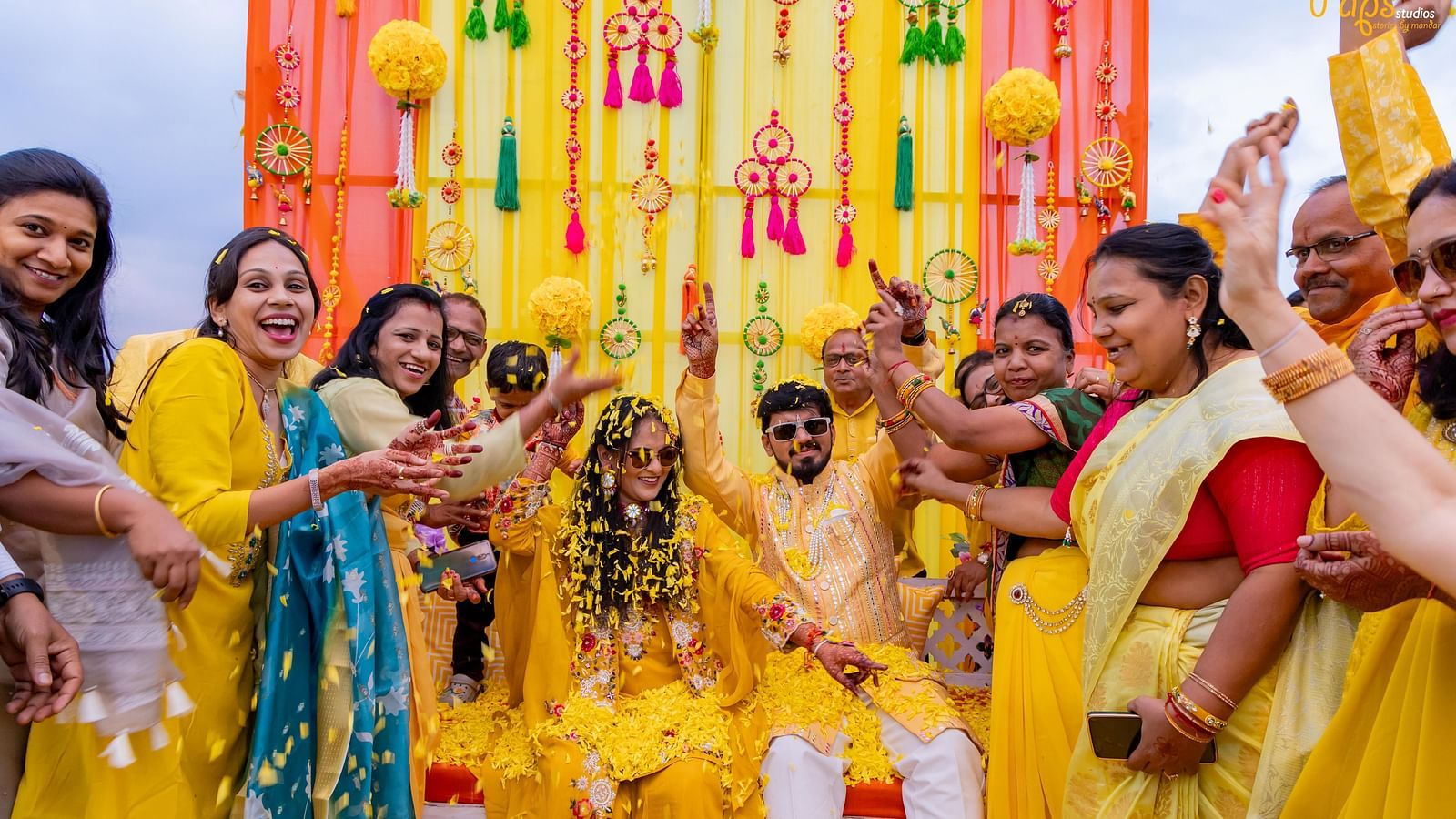 Joyful women in sarees dance under colourful decorations, celebrating with raised hands in what appears to be a festive gathering - The Grand Legacy Resort and Spa