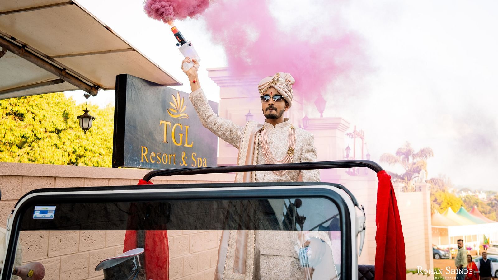 A groom in traditional attire rides in a decorated vehicle, with smoke in the air, possibly during his baraat procession - The Grand Legacy Resort and Spa
