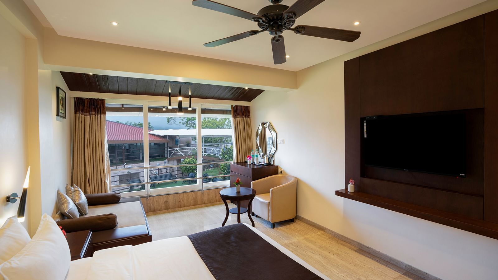 Room with large bed, ceiling fan, sofa, and window view - The Grand Legacy Resort & Spa