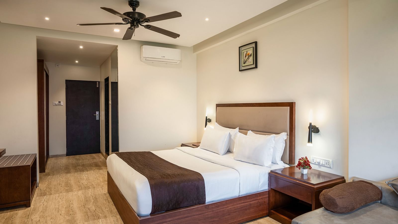 Shot of a comfortable room at our resort featuring a king size bed, side table, a couch | Shot of the facade of the resort clicked from the lush green lawn during a cloudy day | The Grand Legacy Resort and Spa
