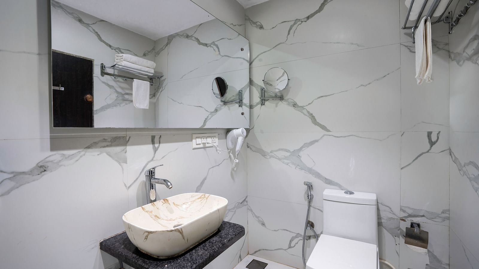 Modern bathroom with wall-mounted fixtures, mirror, and marble-style walls  - The Grand Legacy Resort & Spa