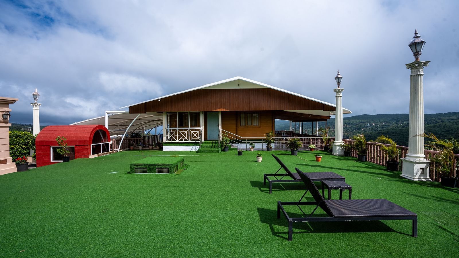 Image of the facade of the property with a lush green lawn and two chairs | The Grand Legacy Resort and Spa