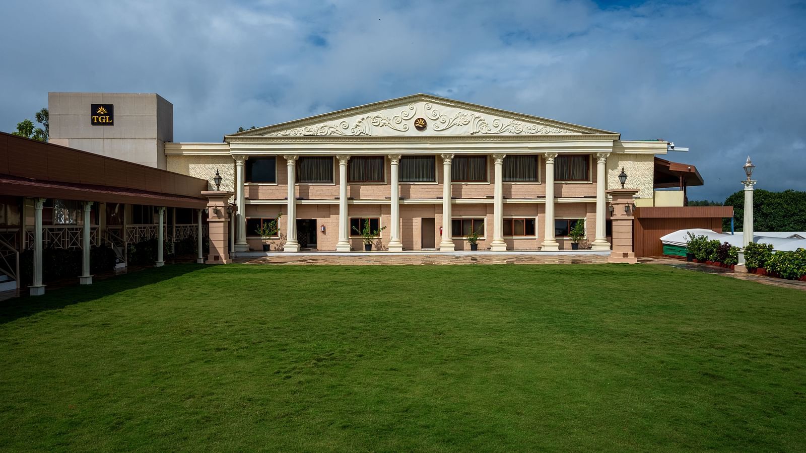 A vast lawn area at The Grand Legacy Resort and Spa, featuring a building in the center under a cloudy sky.