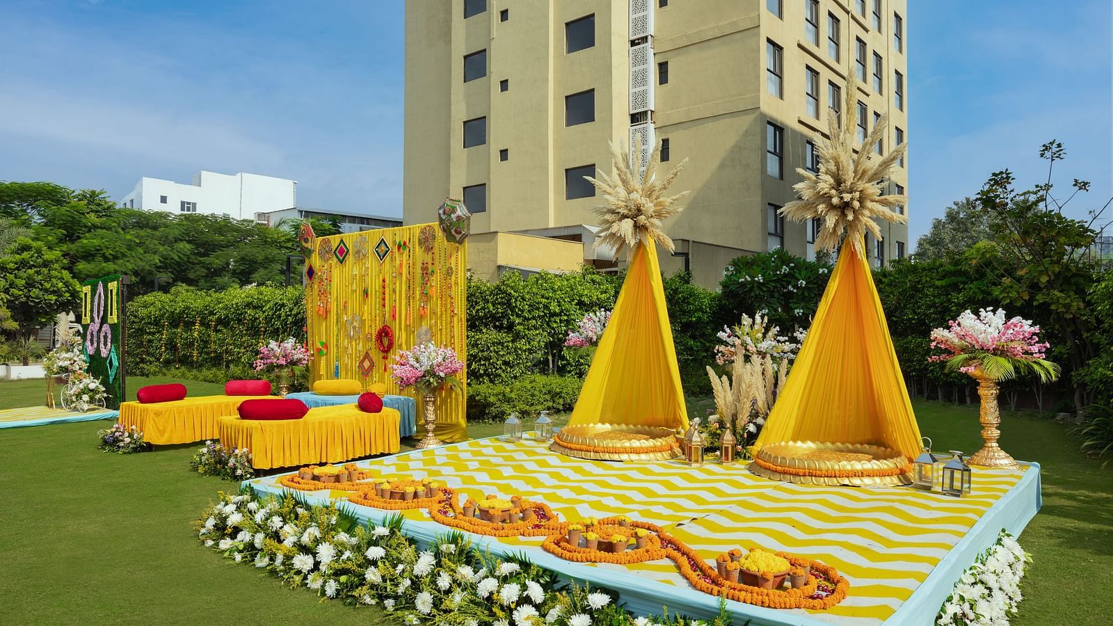 a stage set with two specially decorated seats and more seating arrangements beside the stage - The Hideaway Banquets & Lawns, Greater Noida
