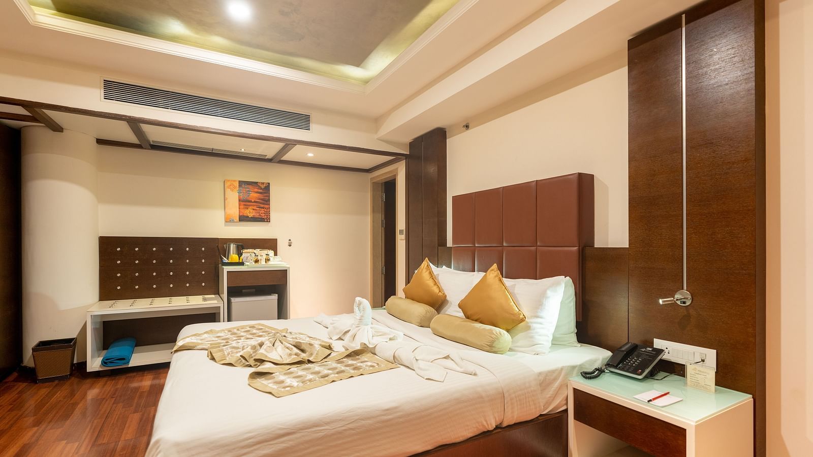 A king size bed with centralised AC and side tables next to the bed inside Club Suite at The President Hotel, Hubli
