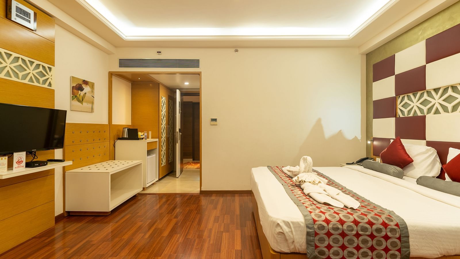 Bedroom with king size bed and tv at The President Hotel, Hubli