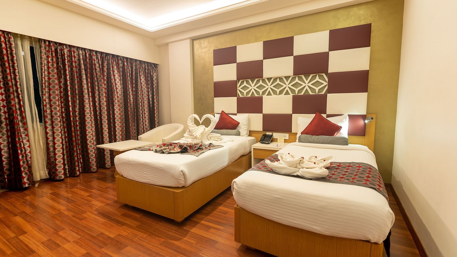 two single beds with a side table at The President Hotel, Hubli