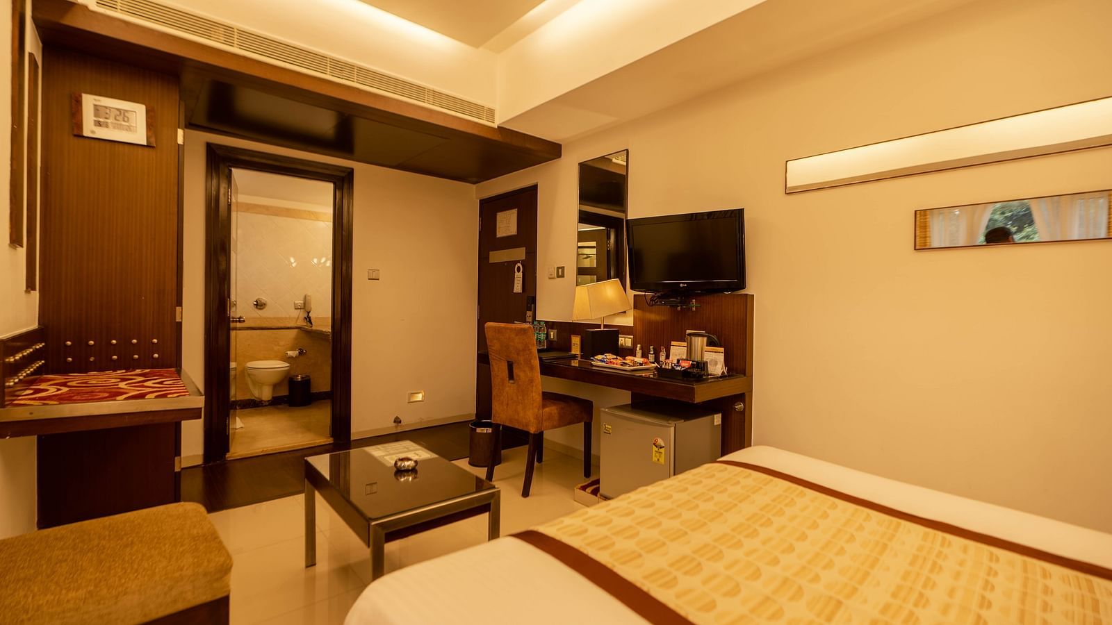 Warm-toned hotel room featuring comfortable beds, a well-equipped work desk, ambient lighting, and a contemporary feel- The President Hotel Jayanagar, Bangalore