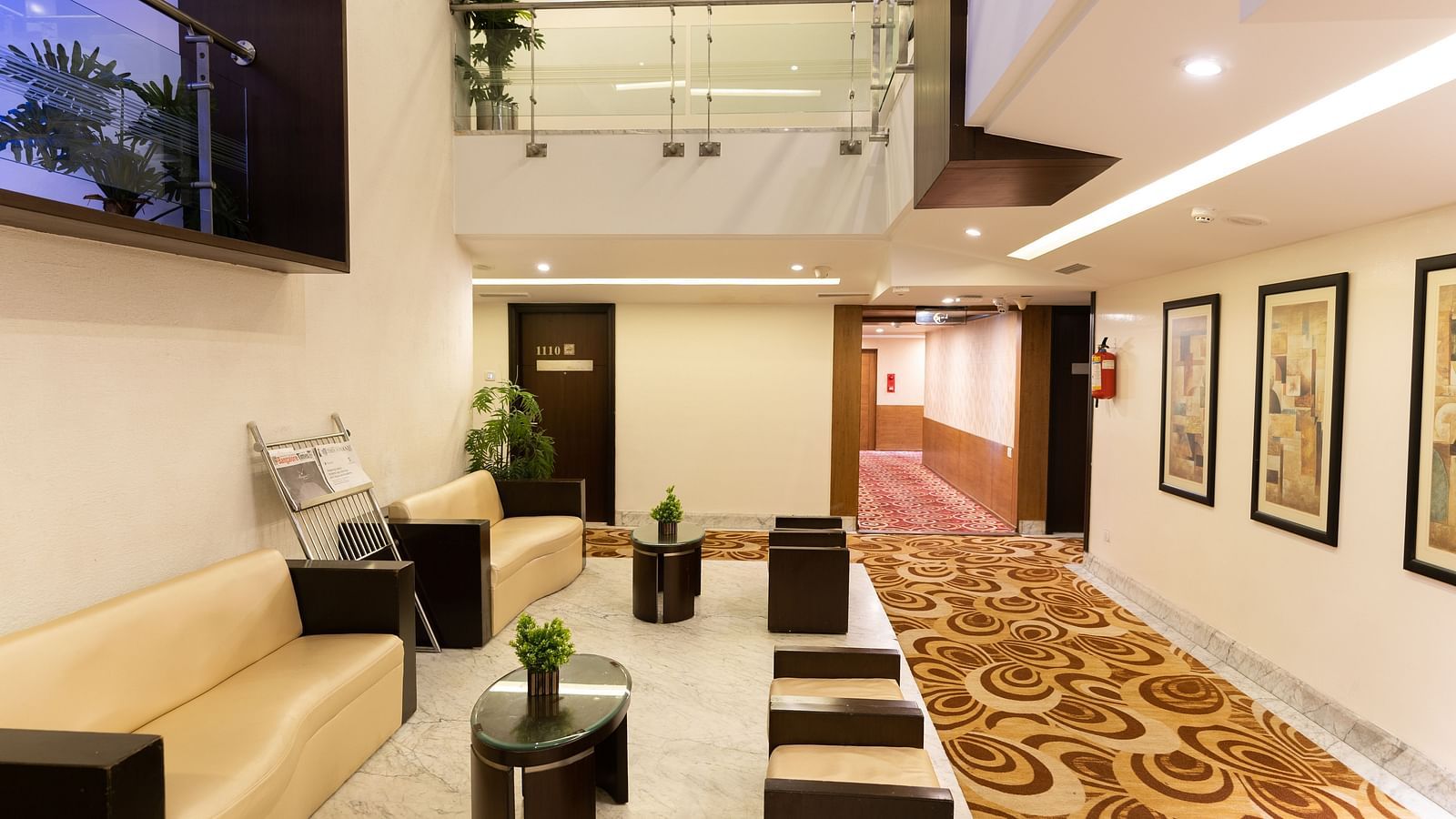 A modern hotel lobby area with comfortable seating, decorative plants, and contemporary art under a bright and welcoming atrium - The President Hotel Jayanagar, Bangalore