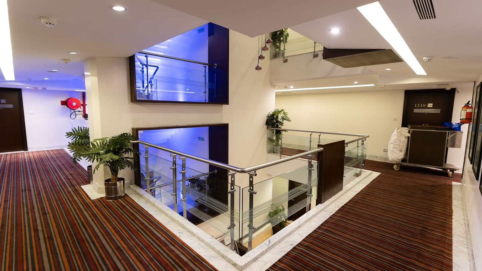 Spacious and modern hotel lobby with glass balustrades, plush seating areas, and a warm, welcoming atmosphere for guests- The President Hotel Jayanagar, Bangalore