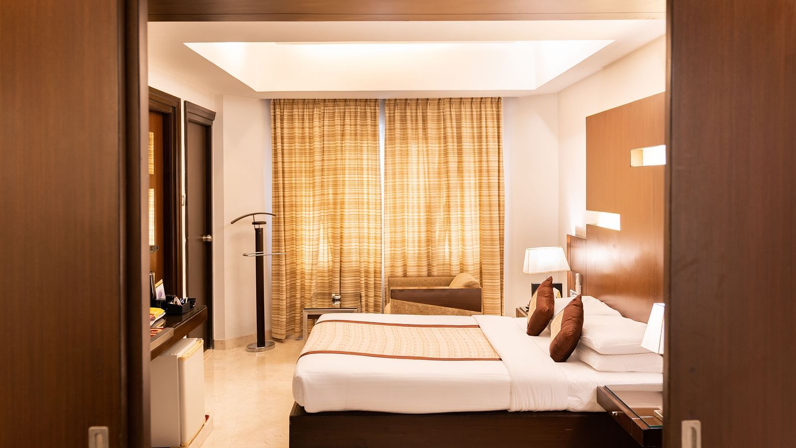  A side view of the cosy room with plushy bed at The President Hotel Jayanagar, Bangalore