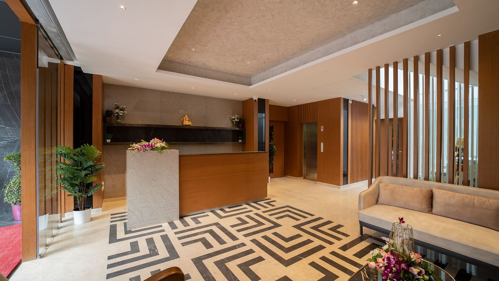 An image of reception area with geometric floor design and wooden slat - The President Hotel, Kumara Park, Bangalore